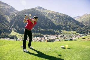 mężczyzna huśtający kijem golfowym na wzgórzu w obiekcie Haus Fischer w mieście Pettneu am Arlberg