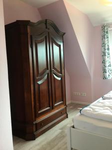- une chambre avec une armoire en bois à côté d'un lit dans l'établissement FeWo Carstensen, à Fehmarn
