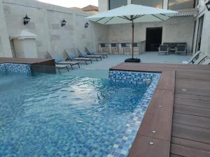 a pool with a pool table, chairs and umbrellas at Mauad Hotel Boutique in Santo Domingo