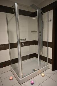 eine Glasdusche im Bad mit Kerzen auf dem Boden in der Unterkunft ApartHotel Legnica - apartamenty z aneksem kuchennym in Legnica