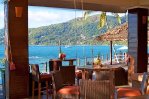 a dining room table with chairs in front of a large body of water at Fisherman's Cove Resort in Beau Vallon