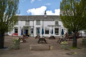 a white building with picnic tables in front of it at The Clovenfords Hotel in Clovenfords