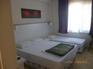 two beds in a small room with a window at Cicek Hotel & Apartments in Fethiye
