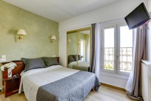 a bedroom with a bed and a large window at Hôtel du Square d'Anvers in Paris
