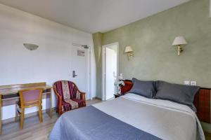 a bedroom with a bed and a desk and a chair at Hôtel du Square d'Anvers in Paris