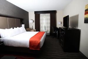 ein Hotelzimmer mit einem Bett und einem Flachbild-TV in der Unterkunft Holiday Inn Express & Suites Monroe, an IHG Hotel in Monroe
