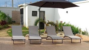 a group of four chairs and an umbrella at Villa Bolati, avec piscine, jacuzzi, jardin et vue in Bonoua