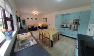 cocina y sala de estar con mesa y fregadero en Moyola River Cottage, en Magherafelt