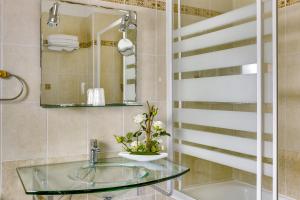 a bathroom with a glass sink and a mirror at Hôtel du Square d'Anvers in Paris