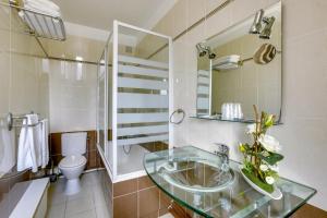 a bathroom with a glass sink and a toilet at Hôtel du Square d'Anvers in Paris