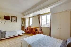 a bedroom with two beds and a desk and a window at Hôtel du Square d'Anvers in Paris
