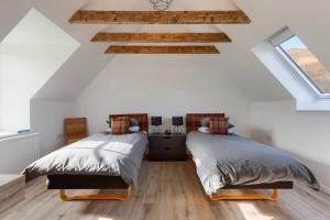 two beds in a bedroom with white walls and wooden floors at Dalveich Cottage w hot tub & stunning views in Lochearnhead