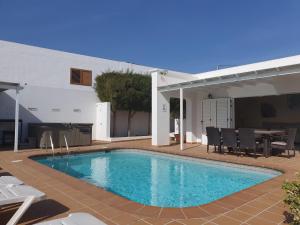 a swimming pool in front of a house at FUN FAMILY VILLA-CRAZY GOLF COURSE-HEATED POOL-COCKTAIL BAR-JACUZZI-GAMES ROOM-WIFI &UK TV in Puerto del Carmen