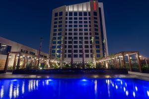 Movenpick Hotel and Residences Riyadh في الرياض: مبنى طويل وبه أضواء أمام مبنى