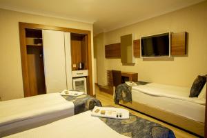 a hotel room with two beds and a flat screen tv at Bursa Palas Hotel in Bursa