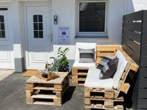 a patio with a couch and a chair on a pile of pallets at ☆FEWO ALTES KINO - MODERN - QUIET - 65M² - TV - NETFLIX - WLAN☆ in Momlingen