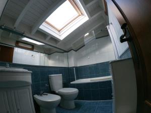 a bathroom with a toilet and a sink and a skylight at El Balcon del Horreo in Piloña