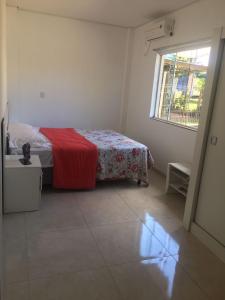 een slaapkamer met een bed met een rode deken en een raam bij Pousada Ágata in Ametista do Sul