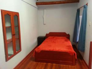ein kleines Schlafzimmer mit einem roten Bett und einem Fenster in der Unterkunft OkiDoki Cusco Hostal in Cusco