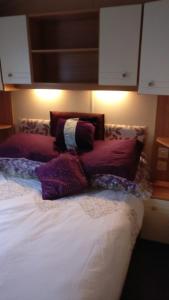 a bed with purple pillows on top of it at 8 BERTH DELUXE CARAVAN ML88 GOLDEN PALM CHAPEL ST LEONARDs in Chapel Saint Leonards