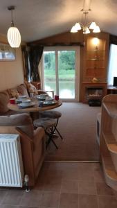 a living room with a couch and a table at 8 BERTH DELUXE CARAVAN ML88 GOLDEN PALM CHAPEL ST LEONARDs in Chapel Saint Leonards