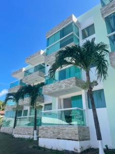 a building with palm trees in front of it at Mar e Sol Residencial em Jacuma PB in Conde