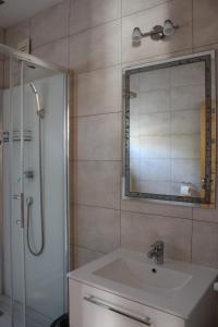La salle de bains est pourvue d'un lavabo, d'une douche et d'un miroir. dans l'établissement Domek Pod Wierzbą, à Sikorzyno