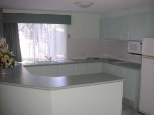 a kitchen with a stove, refrigerator, sink and dishwasher at Runaway Bay Motor Inn in Gold Coast
