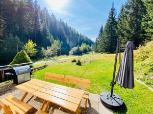 a picnic table with an umbrella and a grill at Wildbach Chalet Turrach in Turracher Hohe