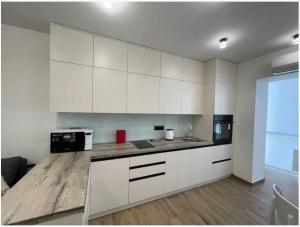 a kitchen with white cabinets and a black microwave at Lux 1-bedroom beautiful apartment Most City Central area in Dnipro +2 photos
