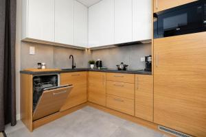 a kitchen with wooden cabinets and a dishwasher at Klifowa Premium Resort with SPA, Fitness & Kids Club by Renters in Rewal