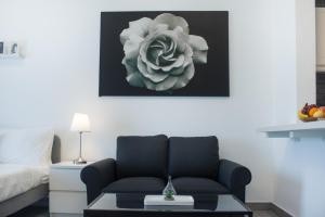 a living room with a couch and a flower painting on the wall at LUXE Studio Near Discovery Gardens Metro Station in Dubai