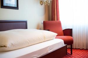 a bedroom with a bed and a red chair at Hotel Haus am Zoo in Düsseldorf