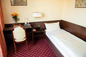 デュッセルドルフにあるホテル ハウス アム ズーのベッド、デスク、椅子が備わるホテルルームです。