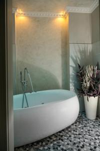 a white tub in a bathroom with two potted plants at Albergo Rossini 1936 in Bologna