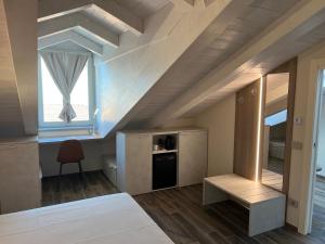 クーネオにあるOsteria Senza Fretta Rooms for Rentのベッドと窓付きの屋根裏部屋