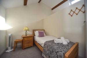 a small bedroom with a bed and a night stand at Church Farm Holiday Cottages - Winnets Cottage in Ashbourne