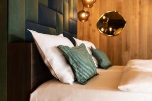 a bedroom with a bed with white pillows and a mirror at Hotel Fanes in San Cassiano