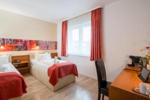 a hotel room with two beds and a desk at Arador-City Hotel in Bad Oeynhausen