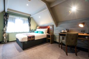 um quarto com uma cama, uma secretária e uma cadeira em The Pine Marten by Innkeeper's Collection em Harrogate