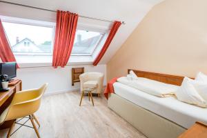 een slaapkamer met een bed, een bureau en een televisie bij Arador-City Hotel in Bad Oeynhausen