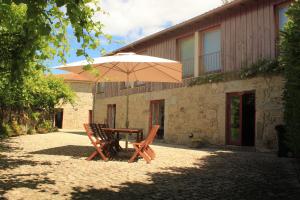 une table et des chaises avec un parasol en face d'un bâtiment dans l'établissement Meiros House Tourism and Nature, à Amares