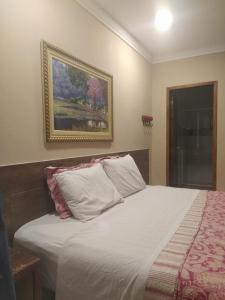 a bedroom with a white bed with a picture on the wall at Pousada Casa do Bosque in Penedo