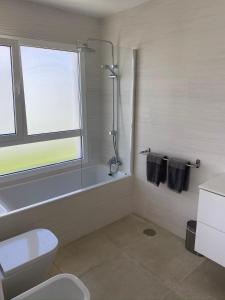 une salle de bain avec baignoire et toilettes et une fenêtre dans l'établissement Villa Ashdene - luxury modern villa with large heated pool wifi uk tv bar & BBQ, à Playa Blanca