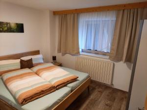 Bett in einem Zimmer mit Fenster in der Unterkunft Ferienwohnung Regensburger in Wenns