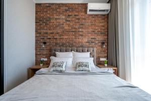 a bedroom with a brick wall and a bed with pillows at Стильная квартира с балконом на 5 Фонтана in Odesa