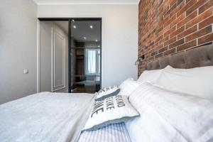 a bedroom with a white bed with a brick wall at Атмосферні 4 квартирина поряд, 5 станція фонтану, з власним балконом fainorent in Odesa