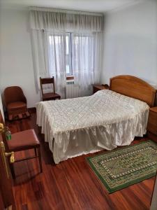 a bedroom with a bed, chair, desk and a lamp at Baires Portomarin in Portomarin
