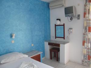 a bedroom with a bed and a desk and a television at Afentoulis Studios 2 in Kefalos