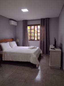 Un dormitorio con una cama grande y una ventana en Armazém do Porto, Chalé Azaléia, en Morretes